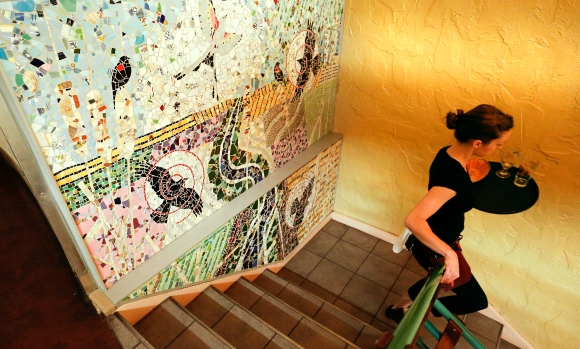 Free State server Elizabeth Cunningham makes her way down the stairs past a wall mosaic created by Lawrence artist Lora Jost. Nick Krug/Journal-World Photo